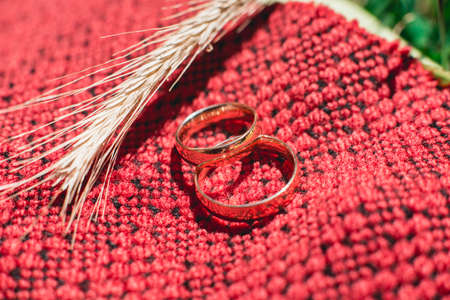 Wedding rings with wheat ears on red handmade fabric.の写真素材
