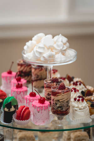 glass stand with cupcakes and other sweets on a wedding candy bar table.の写真素材