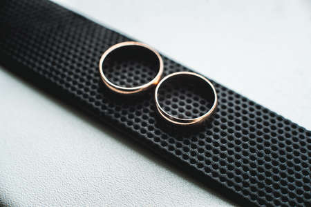 Close up of wedding rings on a black leather belt.の写真素材