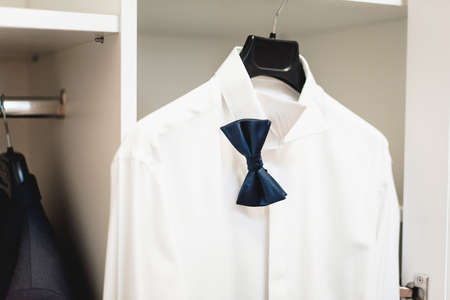 White shirt with bow tie hanging on wardrobe. wedding dayの写真素材