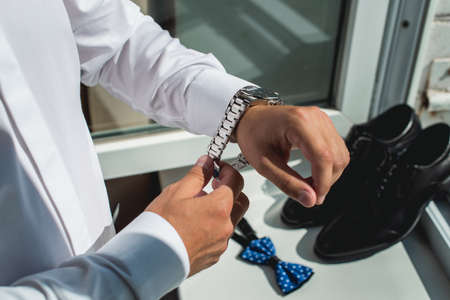 businessman checking time on his wrist watch, man putting clock on hand,groom getting ready in the...