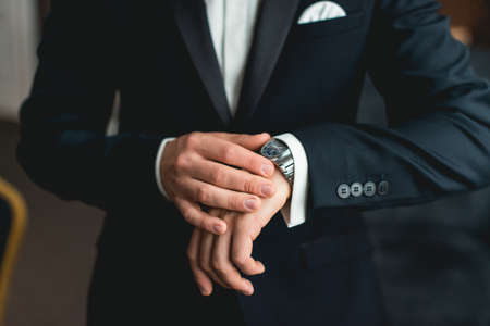 businessman checking time on his wrist watch, man putting clock on hand,groom getting ready in the...