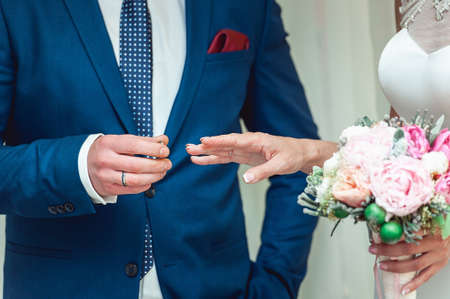 exchanging wedding rings. Groom puts a ring on the bride's finger. groom in a blue suit. The bride's...