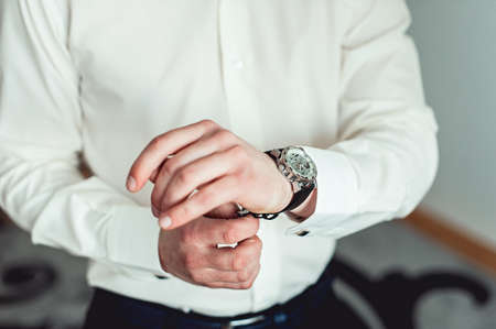 businessman checking time on his wrist watch, man putting clock on hand,groom getting ready in the...
