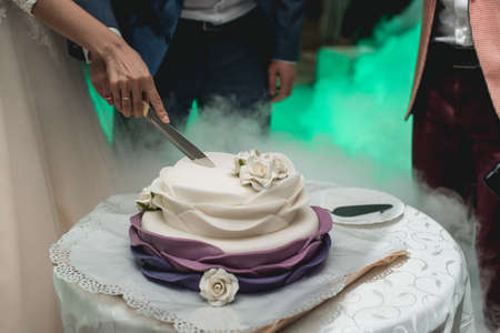 A bride and a groom is cutting their wedding cake. beautiful cake. nicel light. wedding conceptの写真素材