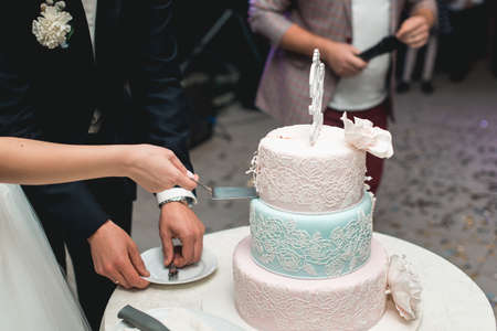 wedding ceremony. the bride and groom make their first case together, cut the beautifull wedding cake decorated with flowerの写真素材