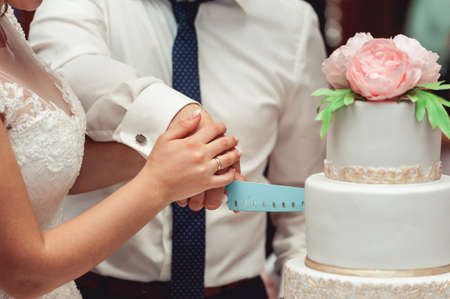 wedding ceremony. the bride and groom make their first case together, cut the beautifull wedding cake decorated with flowerの写真素材