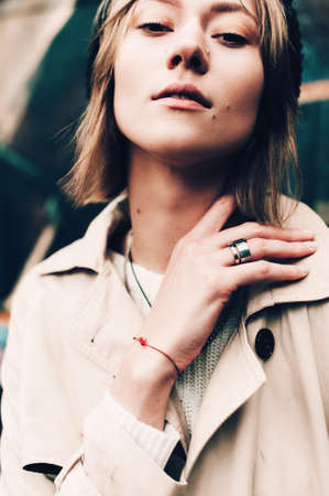 Close-up portrait Beautiful elegant woman wearing beige coat and black hat. Trendy casual outfit....