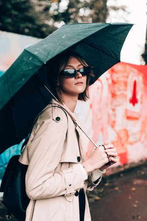 Beautiful woman sitting alone in cafeteria, smoking a cigarette and drinking coffee. Autumn moodの写真素材