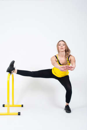 Beautiful woman in purple leggings and top doing exercise for stretching on a white background. Nude make-upの写真素材