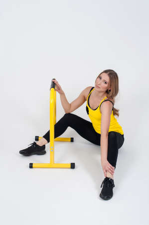 Beautiful woman in purple leggings and top doing exercise for stretching on a white background. Nude make-upの写真素材
