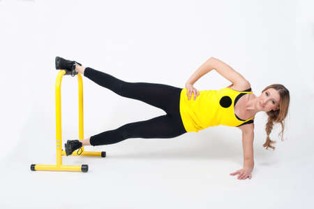 Beautiful woman in purple leggings and top doing exercise for stretching on a white background. Nude make-upの写真素材