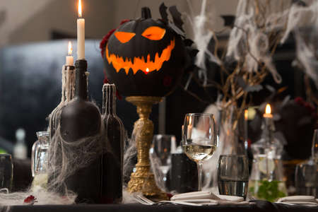 Table set for Halloween dinner. Served holiday table with candles and pumpkin. black tableclothの写真素材