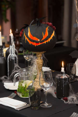 Table set for Halloween dinner. Served holiday table with candles and pumpkin. black tableclothの写真素材