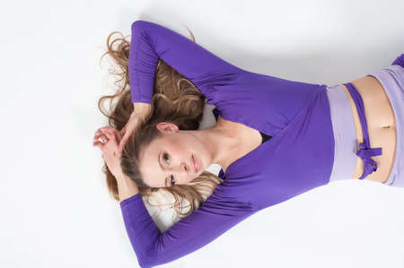 Portrait of a beautiful woman in purple leggings and top posing on a white background. Lite make-upの写真素材
