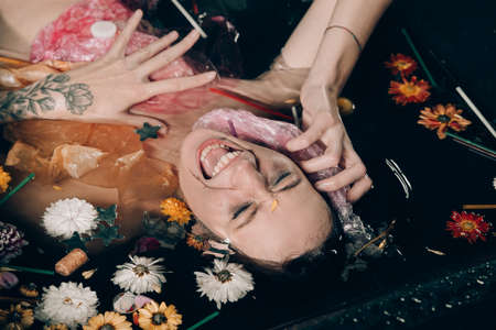 naked scared girl in the black bath full of garbage, environmental or polution concept.の写真素材