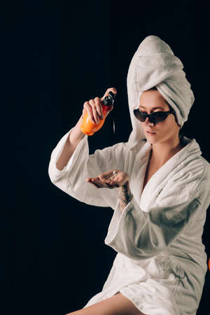 Skin Care, Woman in Sunglasses Applying Cream in Bath Towel after Spa, Treatment Cosmetic Moisturizing Lotion. Black backgroundの写真素材