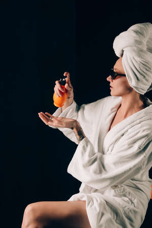 Skin Care, Woman in Sunglasses Applying Cream in Bath Towel after Spa, Treatment Cosmetic Moisturizing Lotion. Black backgroundの写真素材