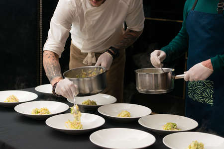 Closeup of chief serving Irish colcannon with bacon served in a white bowl or traditional mashed potato with addition of kale, leek and green onion, close-upの写真素材