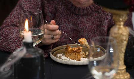 Woman eating delicious apple pie charlotte with caramel on the plate on black tablecloth in a restaurantの写真素材