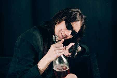 girl in a black jacket posing in a black bath. A bottle of rose champagne wine in hand. Stylish...