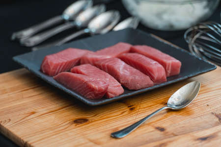 Raw tuna fillet steak on a black ceramic plate. Wooden tableの写真素材