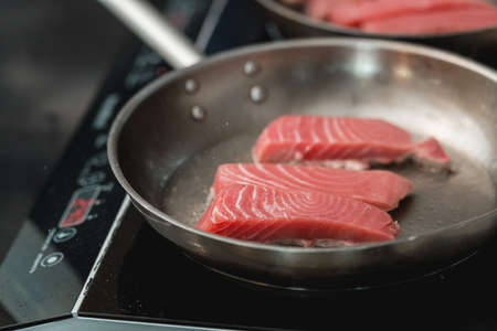 Tuna steak being fried on olive oil on pan on induction stoveの写真素材