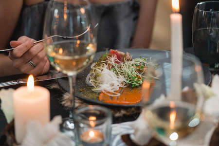 woman eating grilled tuna steak with onion on a gray ceramic plate. Selective focus, close-up.