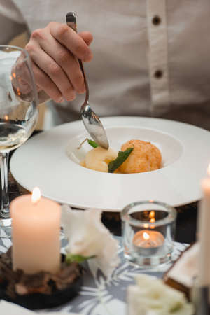 Man eating portion of sorbet with melon balls and mint leaves served on a white platein a...