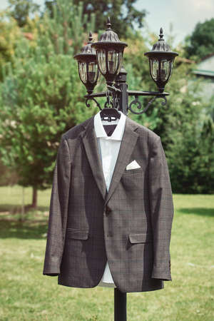 Close-up of man's brown checkered suit hanging on the street lamp in the gardenの写真素材
