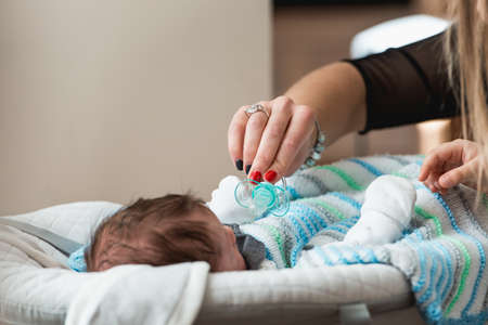 Woman hand with red manicure holds a pacifier as a baby item for reassuranceの写真素材