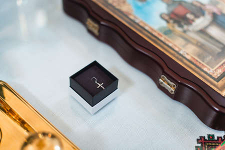 Small golden cross in black box with white top, for small child. Baptism.の写真素材
