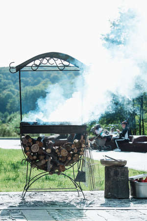 Flaming log in a metal outdoor brazier with ashes and smoke in rural courtyardの写真素材