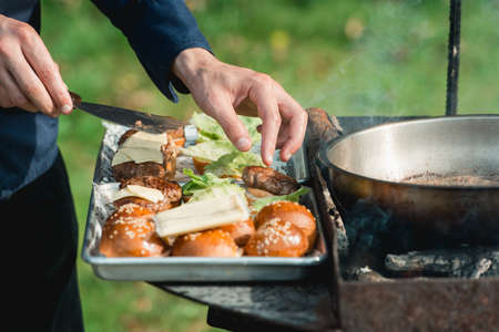 Chef making beef burgers outdoor on open kitchen food festival event. Street food ready to serve on a food stall.の写真素材