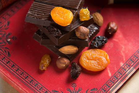 Homemade chocolate bar with raisins on red book background. Concept of healthy homemade sweetsの写真素材