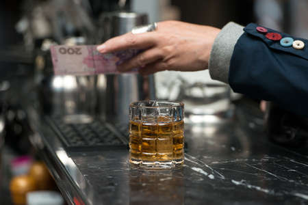 Woman man pays the bartender for the order with a cash.の写真素材