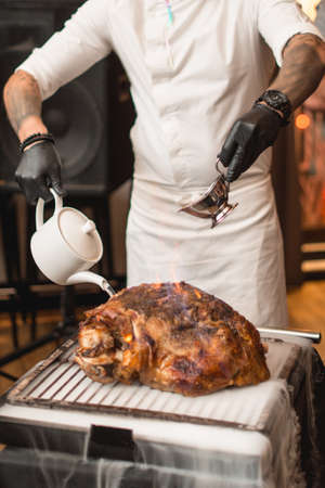 Chef, pouring alcohol into a frying table with meat. Cold ice smokeの写真素材
