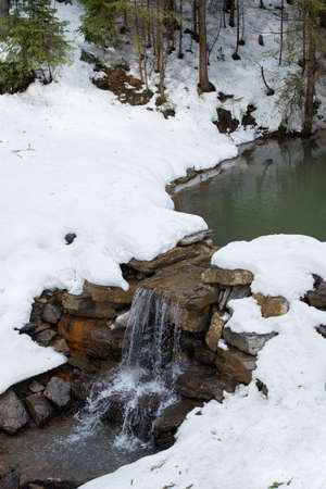 Small river with waterfall in winter in the mountainsの写真素材