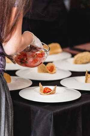 Hand of a girl puts tomato in tacos. The chef at the restaurant is going to make Spicy Shrimp Tacos with Coleslaw and Salsa in a Several plates at the same timeの写真素材