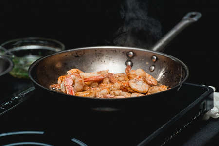 Shrimp on frying pan. Thermal processing of food. Electric cooker in a restaurant. The chef is going to make Spicy Shrimp Tacosの写真素材