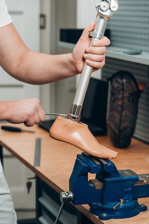 Technician checking artificial limb while at desk in workshop, adjusting it and checking for quality. the latest prosthetic technologiesの写真素材