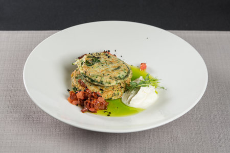 Zucchini pancakes served with sun-dried tomatoes and cream cheese on a light tableclothの写真素材