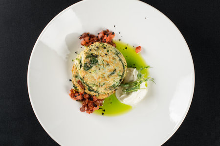 Zucchini pancakes served with sun-dried tomatoes and cream cheese on a black tableclothの写真素材