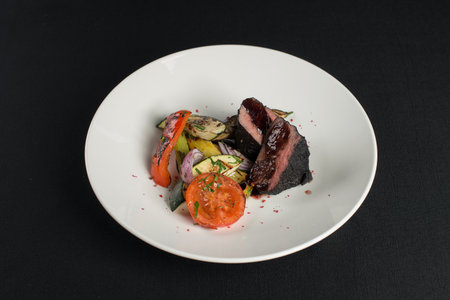 veal tenderloin in ashes with grilled vegetables on a white plateの写真素材