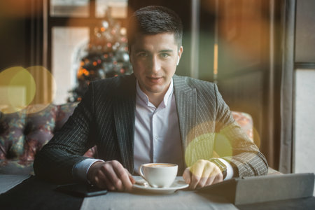 A young and attractive man uses his tablet while drinking coffe in an indoor restaurantの写真素材