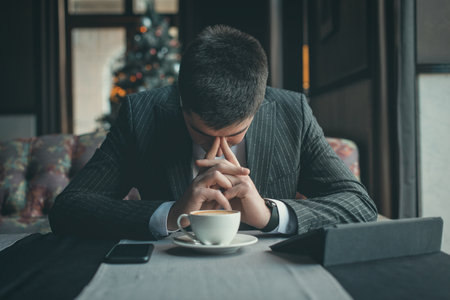 A young and attractive man uses his tablet while drinking coffe in an indoor restaurantの写真素材