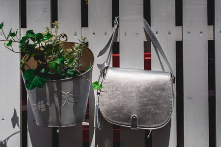 Festive evening small silver bag on a white rustic fence. Luxury accessories and party concept.の写真素材