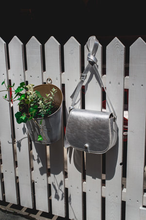 Festive evening small silver bag on a white rustic fence. Luxury accessories and party concept.の写真素材