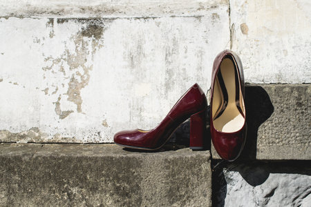 Leather cherry womens shoes on a stone wall. fashion concept, womens shoes, accessories. burgundy womens lacquered leather shoesの写真素材