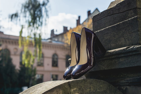 Leather cherry womens shoes on a stone wall. fashion concept, womens shoes, accessories. burgundy womens lacquered leather shoesの写真素材